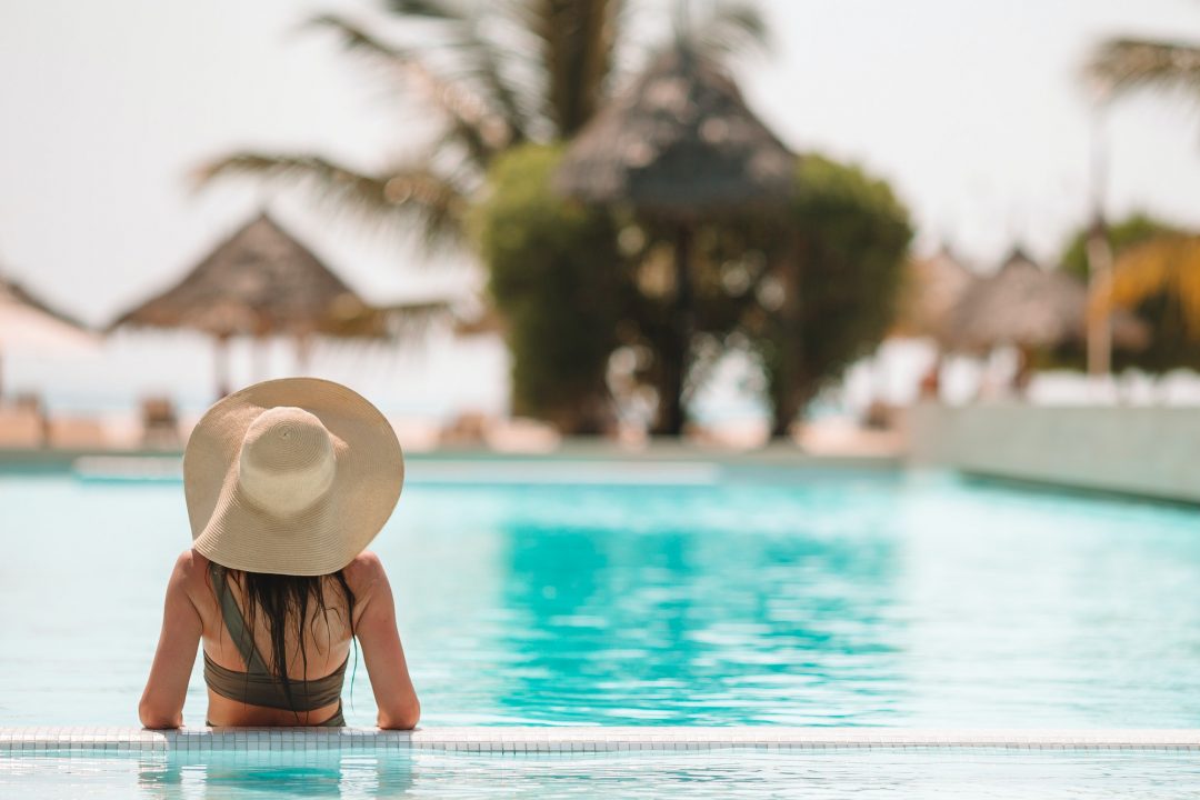 ABOUT US 9 woman relaxing by the pool in a luxury hotel resort enjoying perfect beach holiday vacation